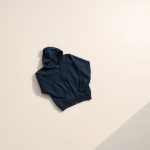 Navy blue black activewear jacket lounge hoodie folded neatly on a neutral surface, top-down flat lay view.