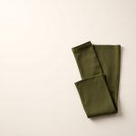 Flat lay of olive green flare leggings black scrunch bum folded neatly on a neutral surface.