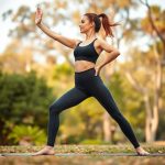 A woman in black high waisted leggings with pockets doing yoga in an Australian park, Heather Grey colour.