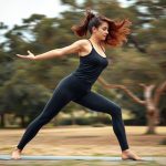 A woman in warrior II pose wearing female leggings with pockets and black top in Charcoal, set in an Australian park.