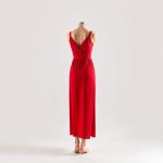 A woman wearing the red First Muse dress for shoulder yoga on a white background.