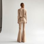 Back view of a model in beige flare stretch pants luna 3, showing the fit on a white background.