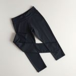 High waisted yoga pants in charcoal folded neatly on a neutral surface, minimalist e-commerce style.