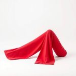 A pair of red organic cotton white flare pants on a white background.