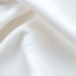 Close-up detail of organic cotton white flare pants showing texture and stitching.