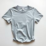Flat lay of a Heather Grey see through yoga tshirt folded on a clean surface.